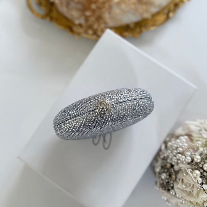 A silver rhinestone-embellished oval clutch purse